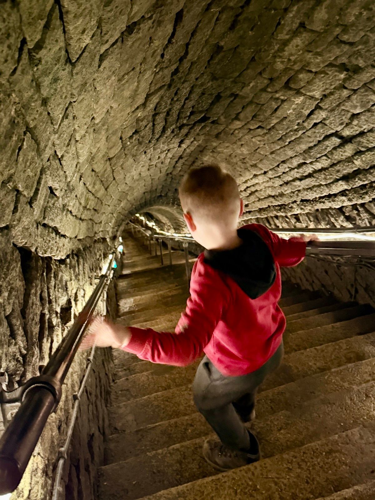 A child descends a stone staircase inside Speedwell Cavern in the Peak District.